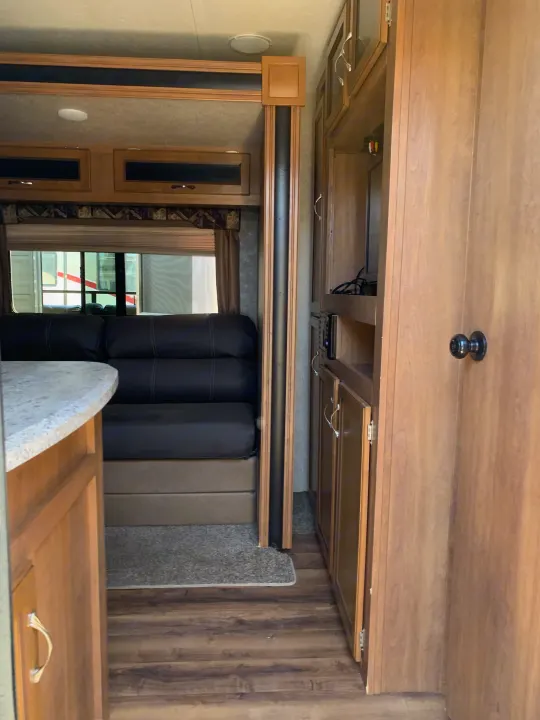 Spacious RV rental interior featuring a living area with black seating, wooden cabinetry, and an entertainment setup.. Coachmen Other 2018