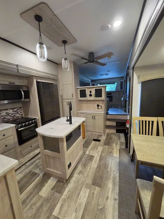 Spacious, modern RV rental interior showcasing a full kitchen with island, dining area, and comfortable living space.. Forest River Sandpiper 2023