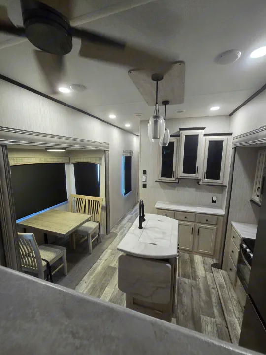 Spacious modern RV rental interior with bright kitchen, island, dining area, and light wood flooring.. Forest River Sandpiper 2023