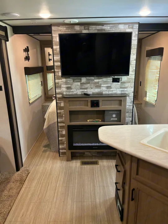 Well-appointed RV rental interior with a cozy electric fireplace, TV, and kitchen counter, showcasing modern amenities.. Keystone RV Hideout LHS 2020