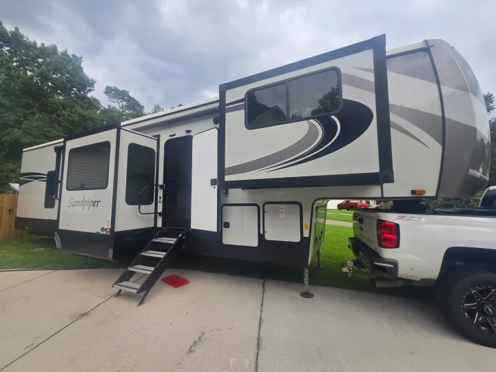 Spacious Sandpiper fifth-wheel RV rental parked with a pickup truck, ready for an outdoor adventure.. Forest River Sandpiper 2023