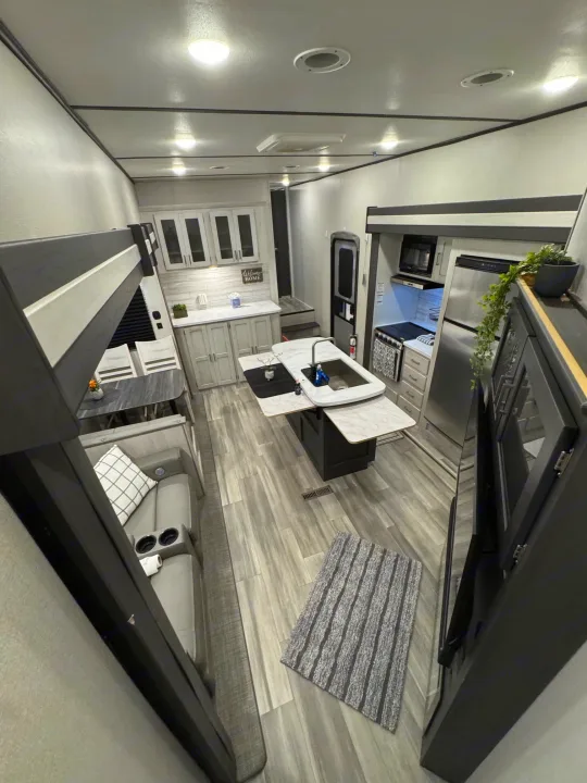 Spacious RV rental interior featuring a modern kitchen, dining area, comfy lounge, and bunk beds.. Keystone RV Sprinter 2022
