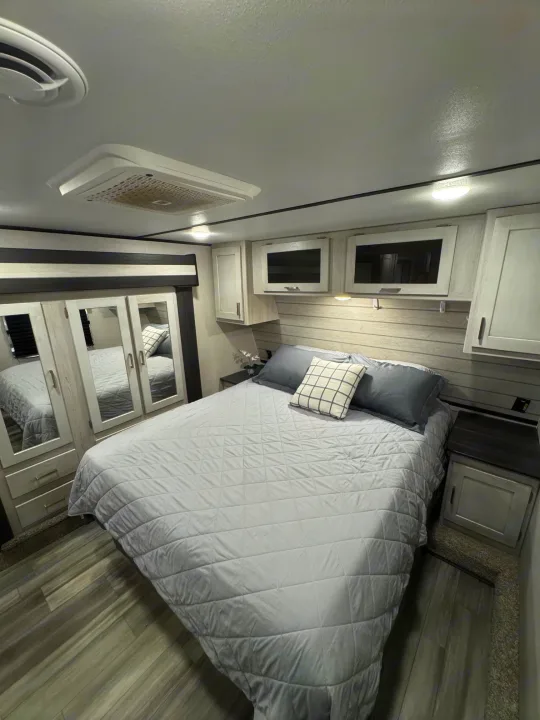 Discover comfort in this modern RV rental bedroom featuring a gray bed, ample storage, and ceiling AC.. Keystone RV Sprinter 2022