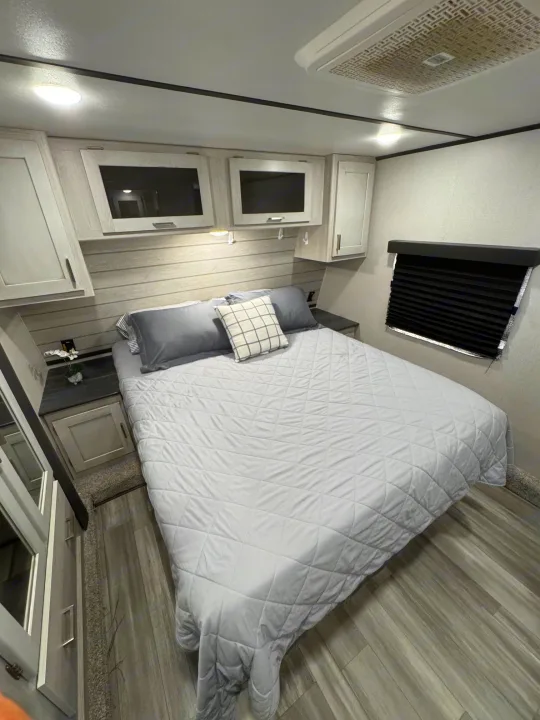 Comfortable RV rental bedroom with modern grey decor, ample storage, and soft lighting for a cozy sleep.. Keystone RV Sprinter 2022