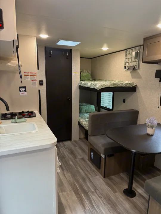 Spacious RV rental interior featuring a kitchen, bunk beds, and dining area with modern wood-look flooring.. Jayco SLX Sport 2025