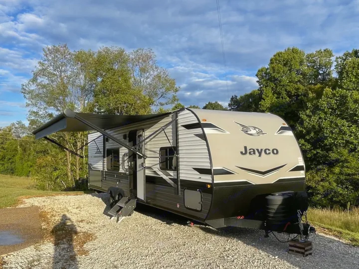 Modern Jayco travel trailer, perfect for an rv rental, parked on a gravel site with extended awning under a cloudy sky.. Jayco Jay Flight 2024