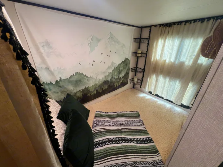 RV rental: Cozy sleeping nook with a mountain tapestry, fluffy bedding, and convenient corner shelves.. Jayco Jay Flight 2024