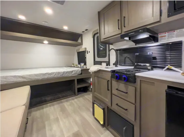 RV rental interior: A modern camper's compact living area with a comfortable bed, equipped kitchen, and storage.. Grand Design Transcend One 151BH 2025