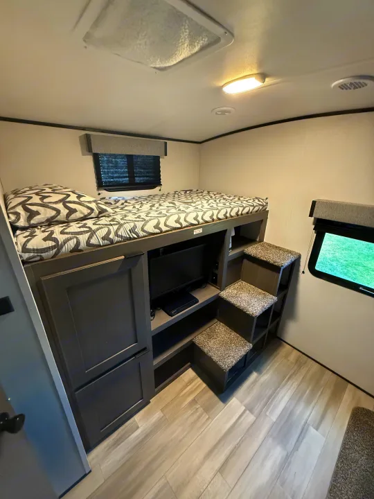 Compact bunk beds in an RV rental, featuring built-in steps, TV, and storage. Ideal for family adventures.. Other Other 2021