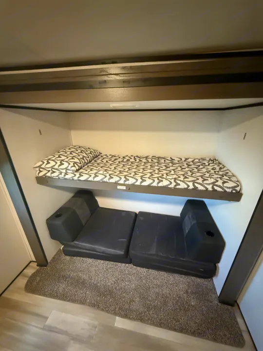 RV rental bunk area features a top bed (275 lb max) and two black modular seats below, offering versatile sleeping.. Other Other 2021