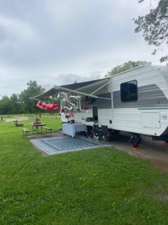 Celebrating with an RV rental! A decorated camper at a grassy campsite with "25" balloons.. Forest River Salem 29BDB 2025