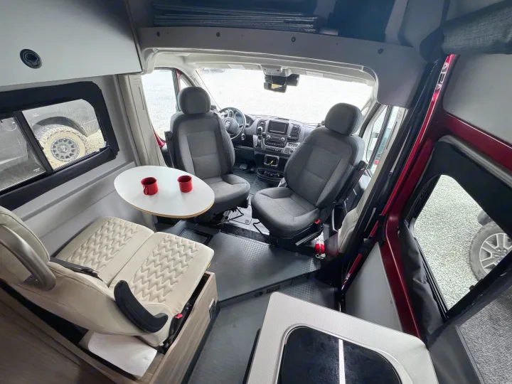 RV rental interior: Swiveling front seats face a dinette table with two red mugs, creating a versatile living space.. Winnebago Winnebago 2023