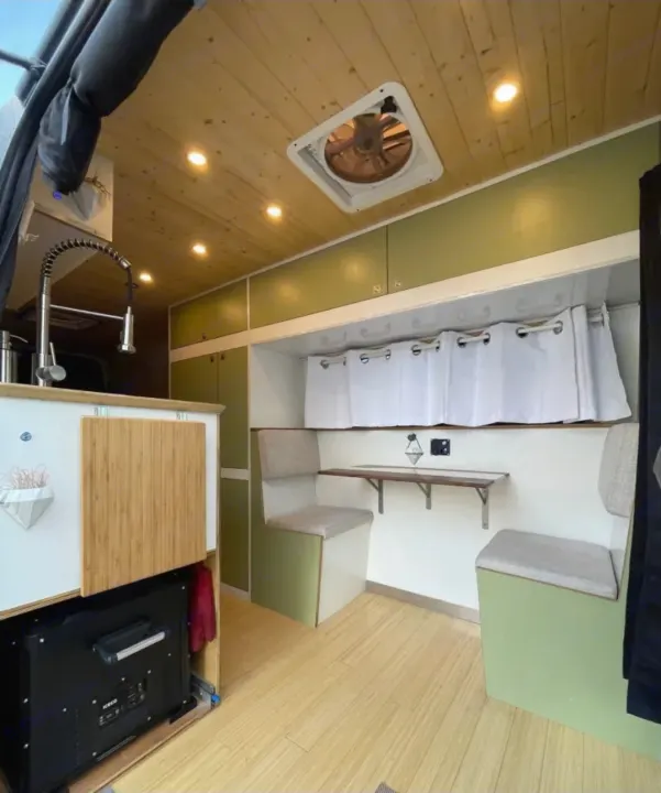 An RV rental's inviting interior featuring a full kitchenette, pull-out fridge, cozy dinette, and wooden accents.. Mercedes Sprinter 2012