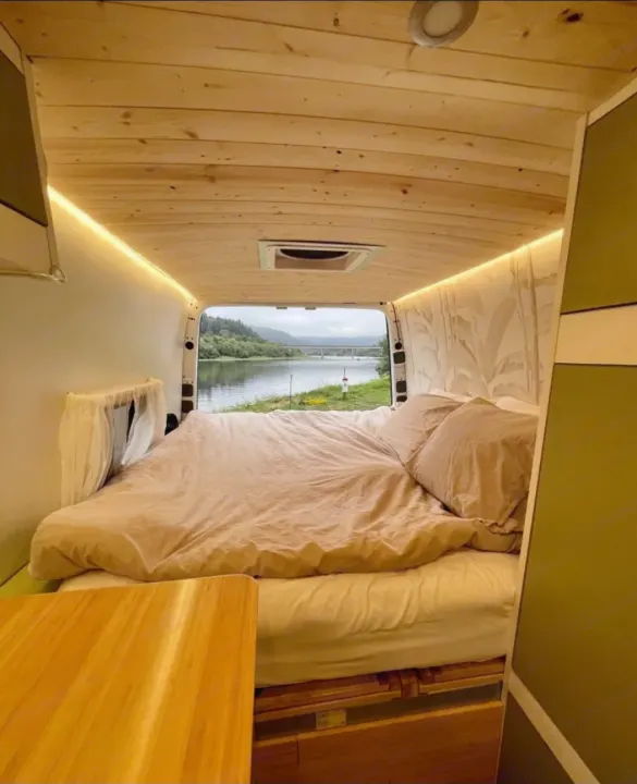 Cozy RV rental bedroom: light wood interior, comfy bed, & stunning river view out the open back doors. Ideal for travel.. Mercedes Sprinter 2012