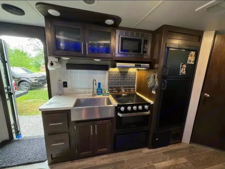 Spacious RV rental kitchen with modern amenities. Perfect for comfortable road trips, featuring full kitchen, microwave, and large fridge.. Forest River Cherokee Grey Wolf 2019