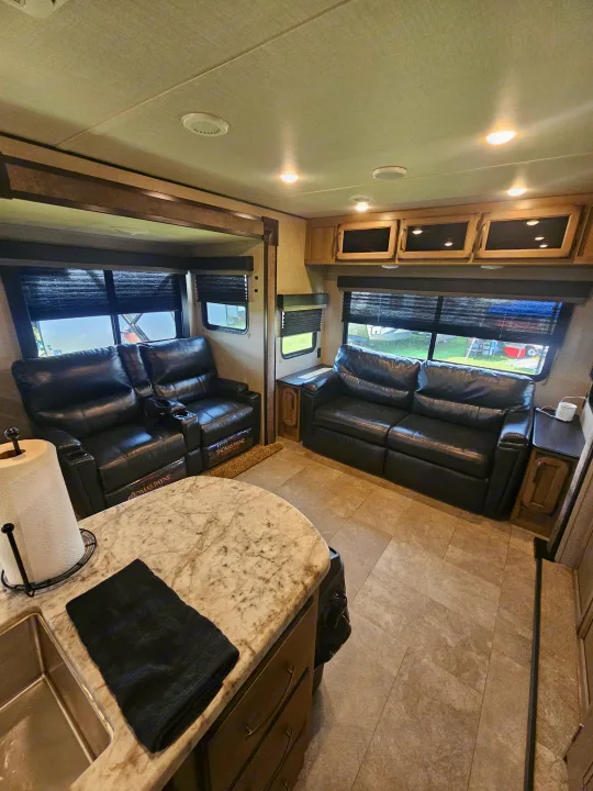 This RV rental boasts a stylish living area with black recliners, sofa, and a functional kitchen.. Grand Design Transcend 2020