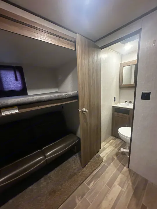 Compact rv rental living: efficient bunk beds & a small bathroom, featuring a toilet, sink & mirror.. Crossroads RV Zinger 2020