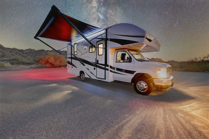 Odyssey Integra SE rv rental under a breathtaking starry night sky, its lights illuminating the desert landscape.. Entegra Coach Odyssey SE 2024