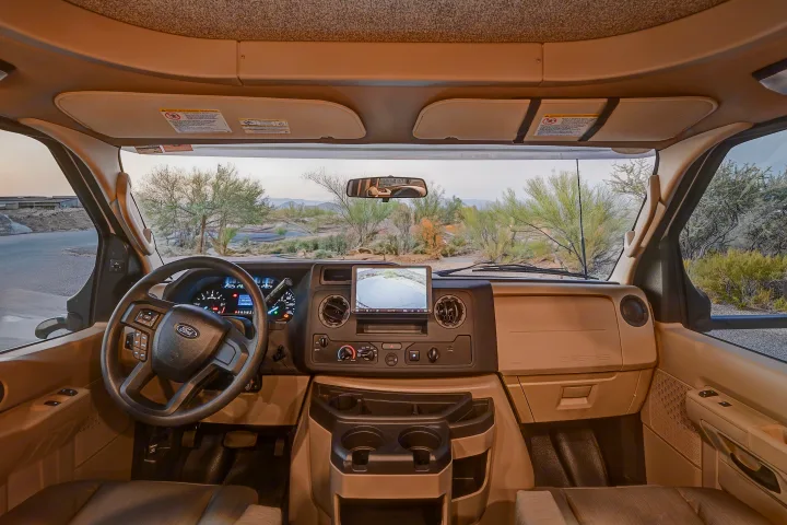 RV rental cockpit view: Ford dashboard, integrated screen, and scenic desert road.. Entegra Coach Odyssey SE 2024