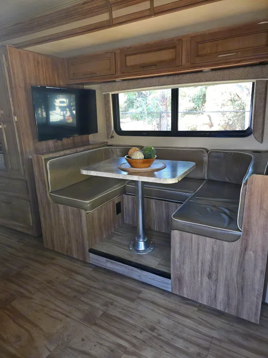 This RV rental features a comfortable dinette with a table, mounted TV, and stylish wood-look flooring, perfect for your trip.. Entegra Coach Odyssey 2019