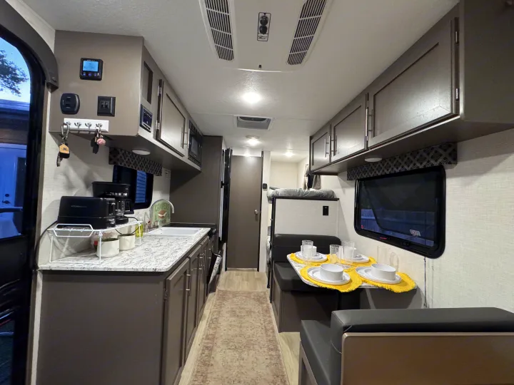 This RV rental interior features a functional kitchen, cozy dinette, and bunk beds, perfect for family adventures.. KZ Sportsman 2024