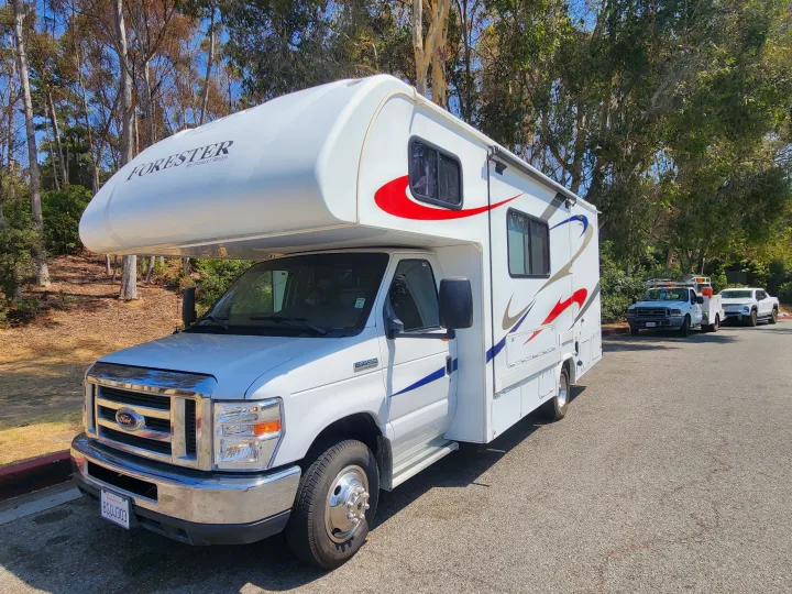 A white Forester Class C RV, ideal for rv rental, is parked on asphalt with trees in the background.. Forest River Forester 2018