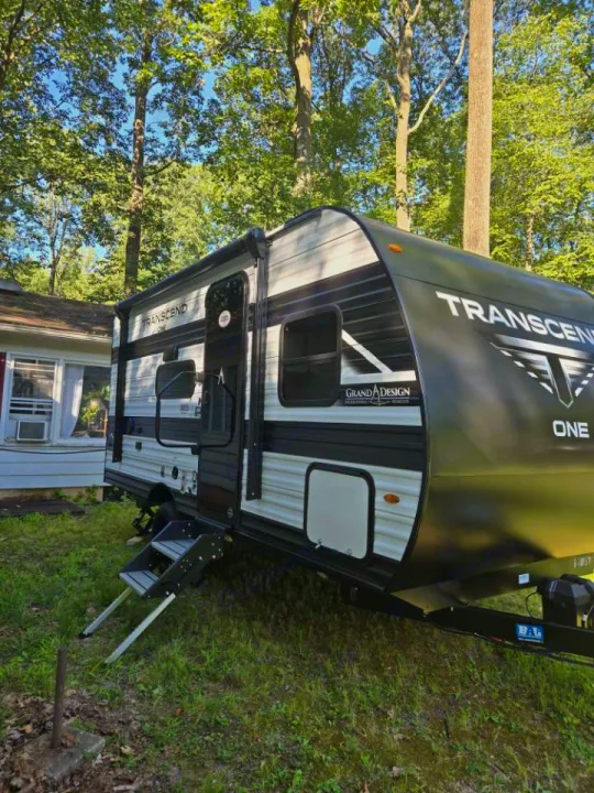 Modern Transcend Grand Design travel trailer RV rental parked on grass with tall trees. Ready for your next adventure!. Grand Design 151BH 2025