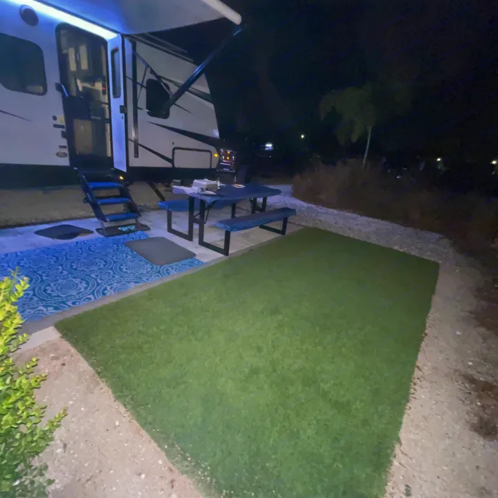 Cozy RV rental campsite at night with illuminated steps, picnic area, and green turf. Perfect for outdoor living.. Keystone RV Bullet Ultra Lite 2022