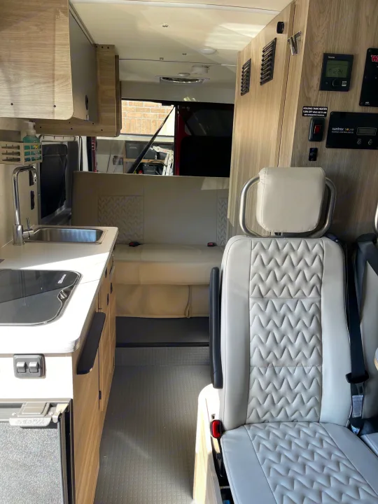Inside an rv rental: A modern kitchenette with sink, bright seating, and a control panel for a comfortable travel experience.. Winnebago Solis 2023