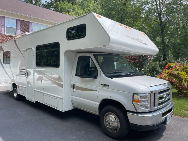 White Class C Majestic RV rental, a spacious motorhome, parked on a paved driveway with a house & green foliage. Ready to go!. Other Other 2017