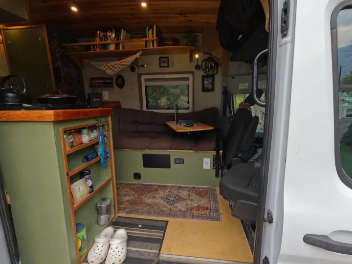 Step into this cozy RV rental's custom interior, featuring a compact kitchen, lounge, and wood-paneled ceiling.. Ford Transit 2017