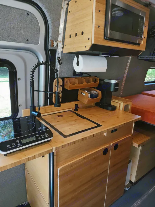 Explore this RV rental's compact bamboo kitchen: sink, cooktop, microwave, and coffee maker in a stylish van interior.. Winnebago Adventure Wagon 2023