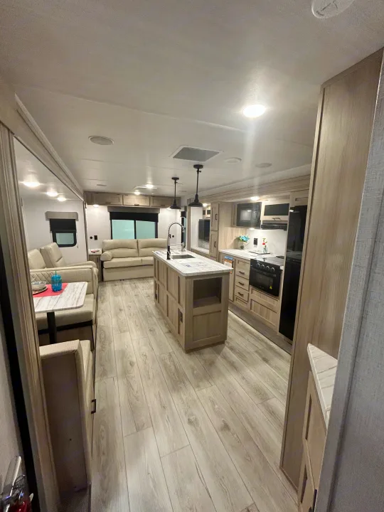Spacious RV rental interior with modern kitchen, island, and living area. Perfect for a cozy getaway.. East to West Della Terra 2024