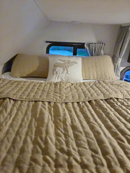 Cozy RV rental bedroom interior featuring a bed with a quilted comforter and a decorative moose pillow.. Forester LE 2022