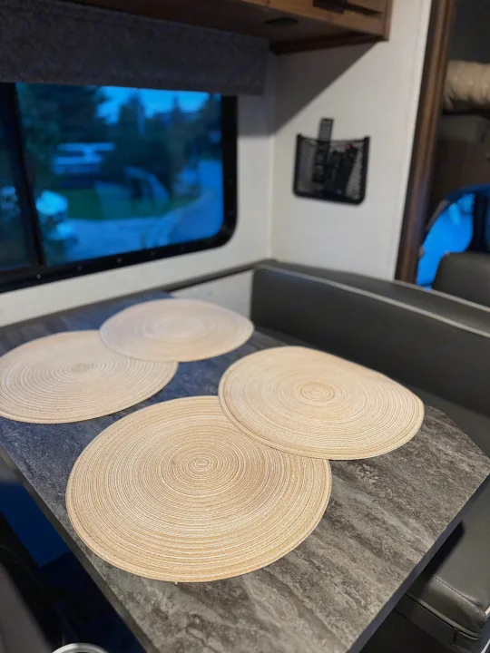 Inside an RV rental: a neat dining table with five light placemats, seen through the window, perfect for travel.. Forester LE 2022