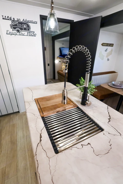 Bright rv rental kitchen featuring a modern sink, roll-up drying rack, and adventure-themed wall art, ready for your journey.. Forest River Puma 2026
