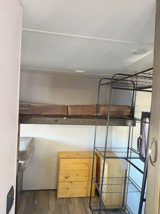RV rental: Compact bunk bed area with a metal ladder, brown mattresses, and natural wood storage drawers inside.. Forest River vibe 2020