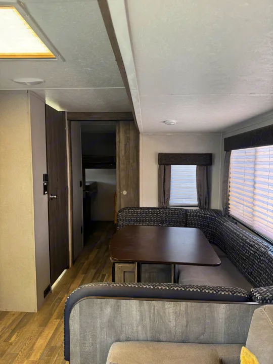 This cozy RV rental interior features a U-shaped dinette, table, and windows with blinds, creating a comfortable living space.. Forest River vibe 2020