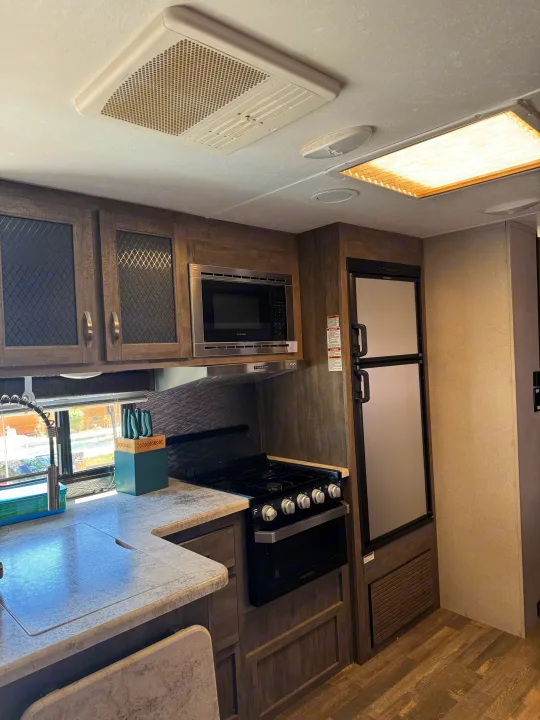 Spacious RV rental kitchen with modern appliances: microwave, stove, oven, fridge, sink, and ample storage.. Forest River vibe 2020