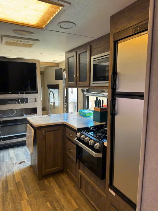 RV rental interior: modern kitchen with Furrion appliances, TV, and living space for comfortable travel.. Forest River vibe 2020