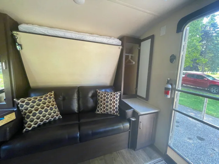 RV rental interior: A dark leather sofa, fold-down bed, closet, and fire extinguisher make for a compact, functional space.. Forest River Wildwood X-Lite 2018