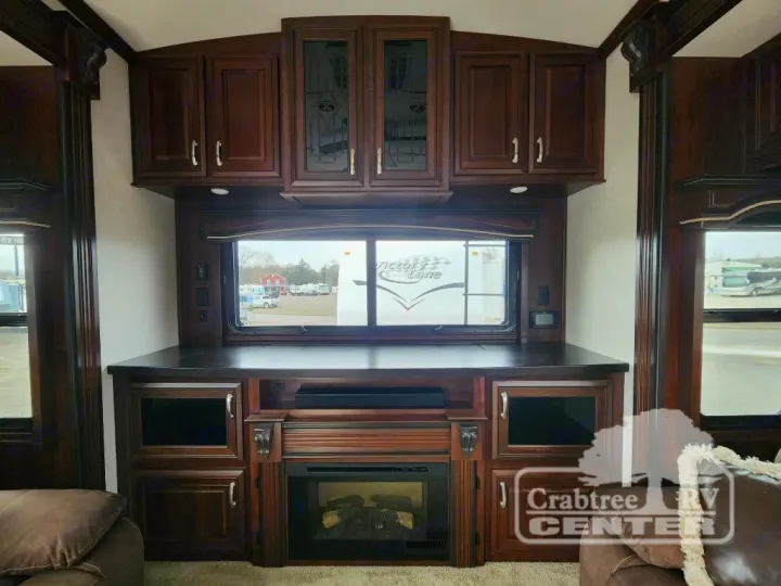 Spacious RV rental living area with dark wood, large window, cozy fireplace, and entertainment setup, ideal for travel.. Jayco Designer 39RE 2017