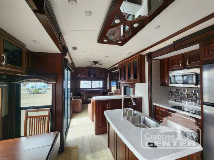 Spacious, luxurious RV rental interior showcasing a full kitchen, living area, and elegant dark wood finishes.. Jayco Designer 39RE 2017