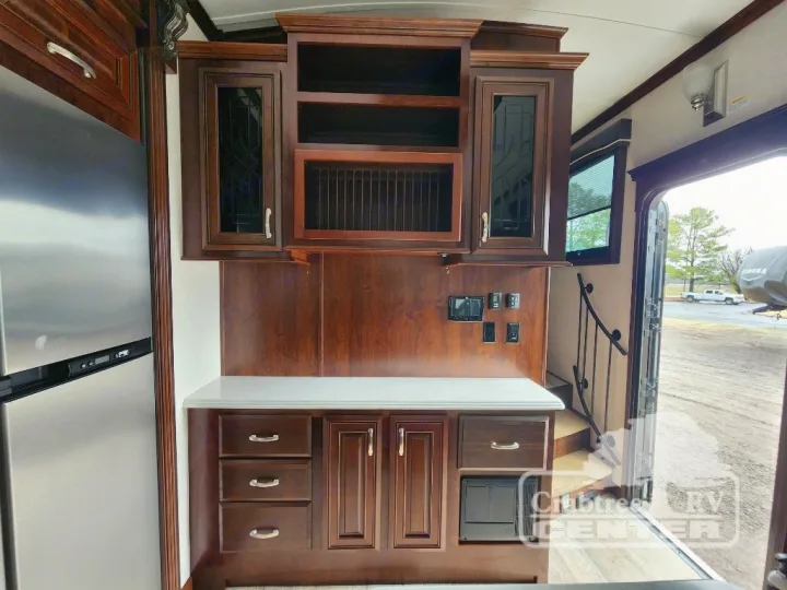 Spacious RV rental kitchen with rich wood cabinetry, stainless fridge, and open entryway.. Jayco Designer 39RE 2017