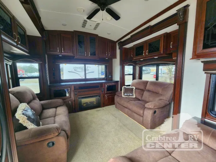 Cozy and spacious RV rental living room with brown recliners, dark wood cabinetry, and an electric fireplace.. Jayco Designer 39RE 2017