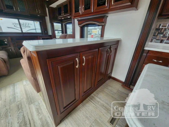 Luxurious RV rental interior with dark wood cabinetry, light countertops, and comfortable seating. Perfect for your travels.. Jayco Designer 39RE 2017