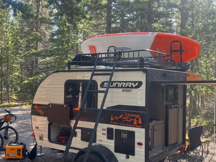 This Sunray Sport RV rental, equipped for outdoor camping adventures, features a roof-top paddleboard and an outdoor kitchen.. Sunset Park RV SunRay 2025