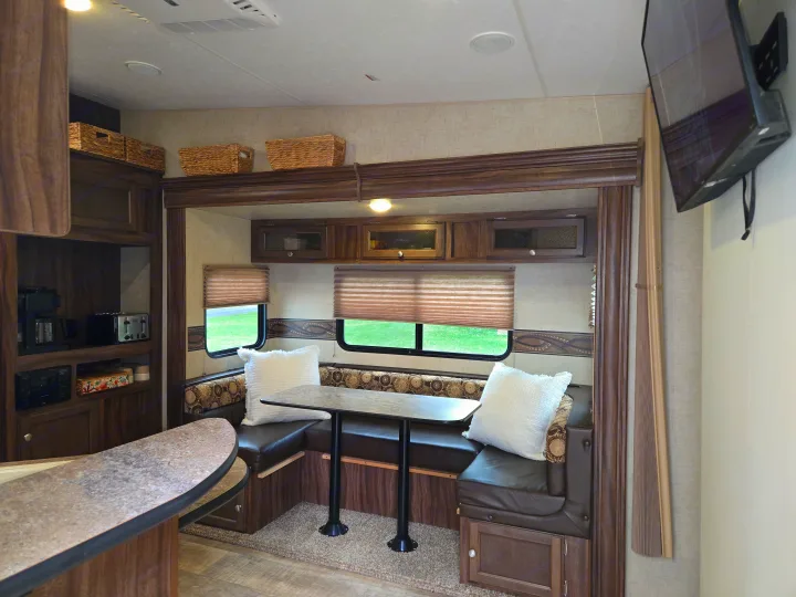 Inviting RV rental interior features a comfy dining booth, well-equipped kitchen area, and ample storage solutions.. KZ Sportmen Sportster Toyhauler 2015
