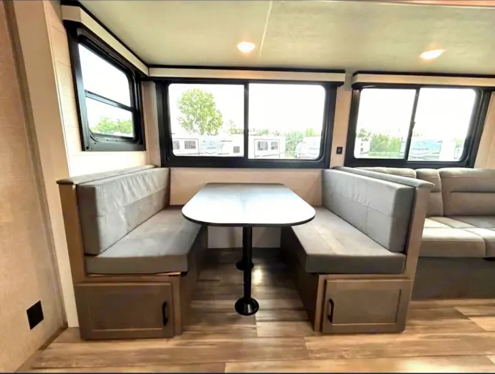 Spacious RV rental interior: modern gray dinette booth with a table, and ample seating by large windows.. Jayco 267BHS 2025