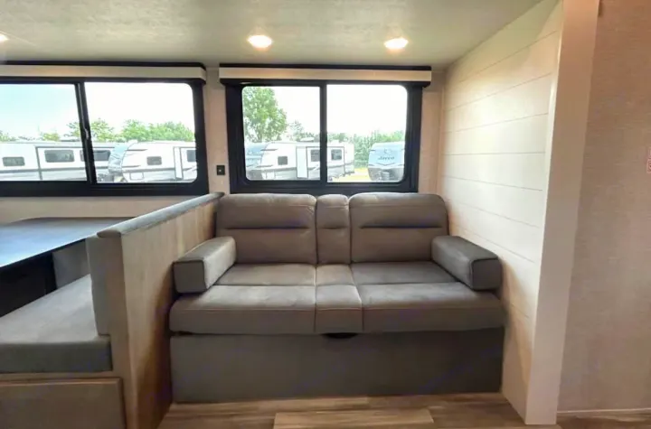 Step inside this RV rental! Features a comfy reclining sofa, dinette, and large windows with views of other RVs.. Jayco 267BHS 2025